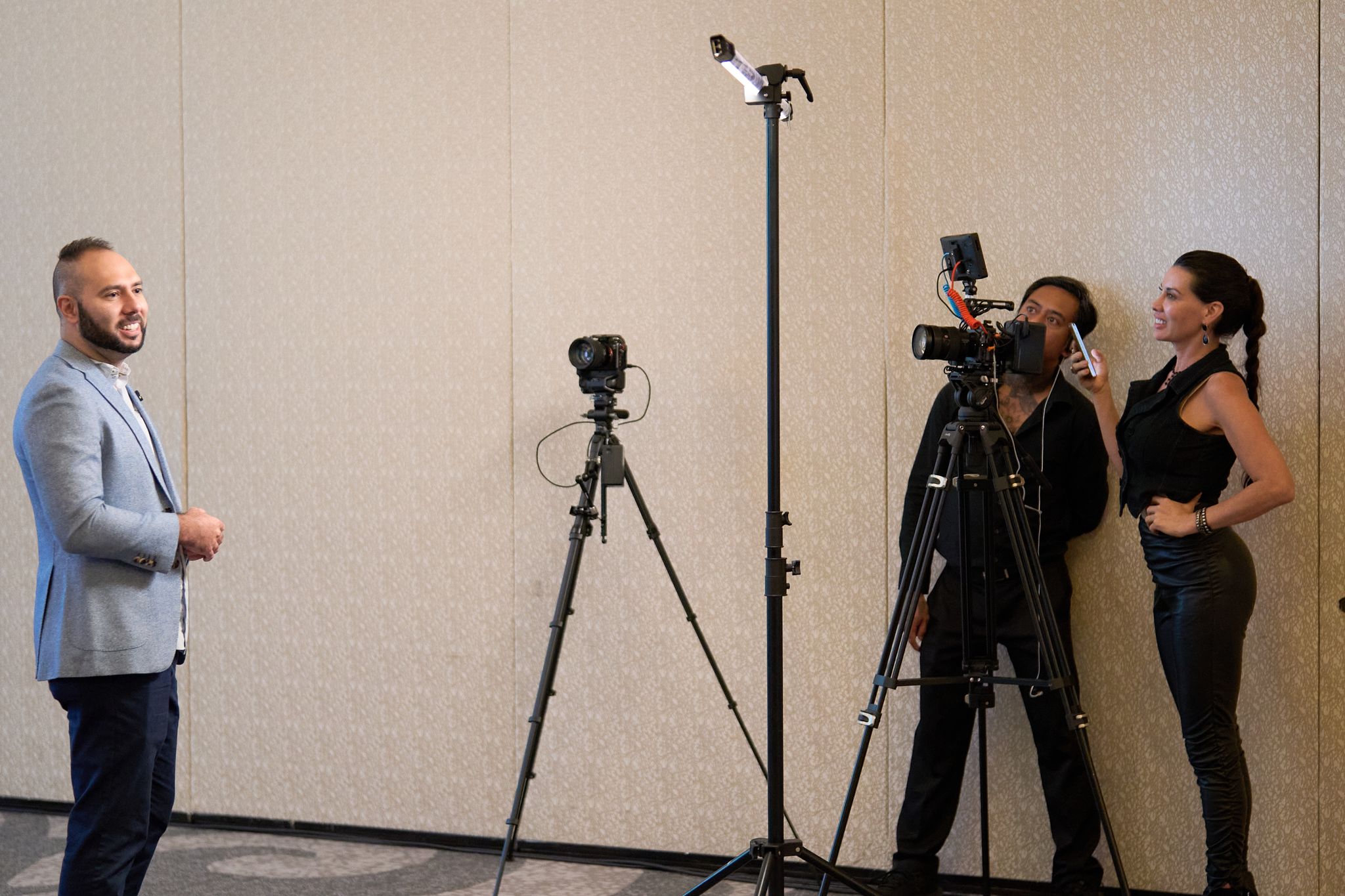 A presenter speaking on stage with the video production crew filming