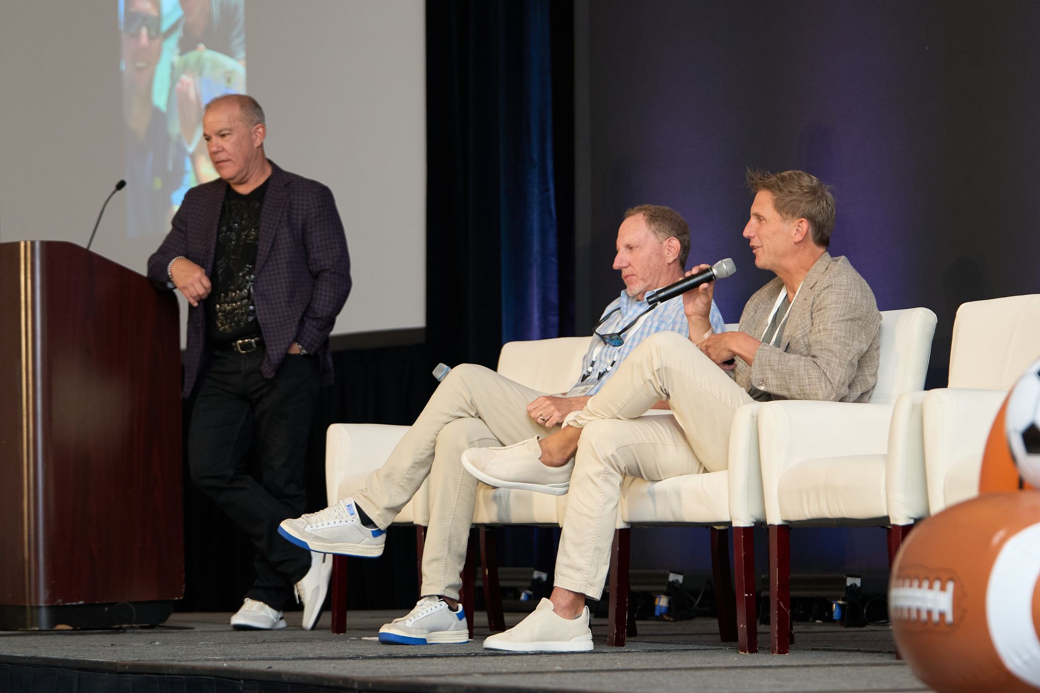 Speaker at the podium beside a seated panel on stage