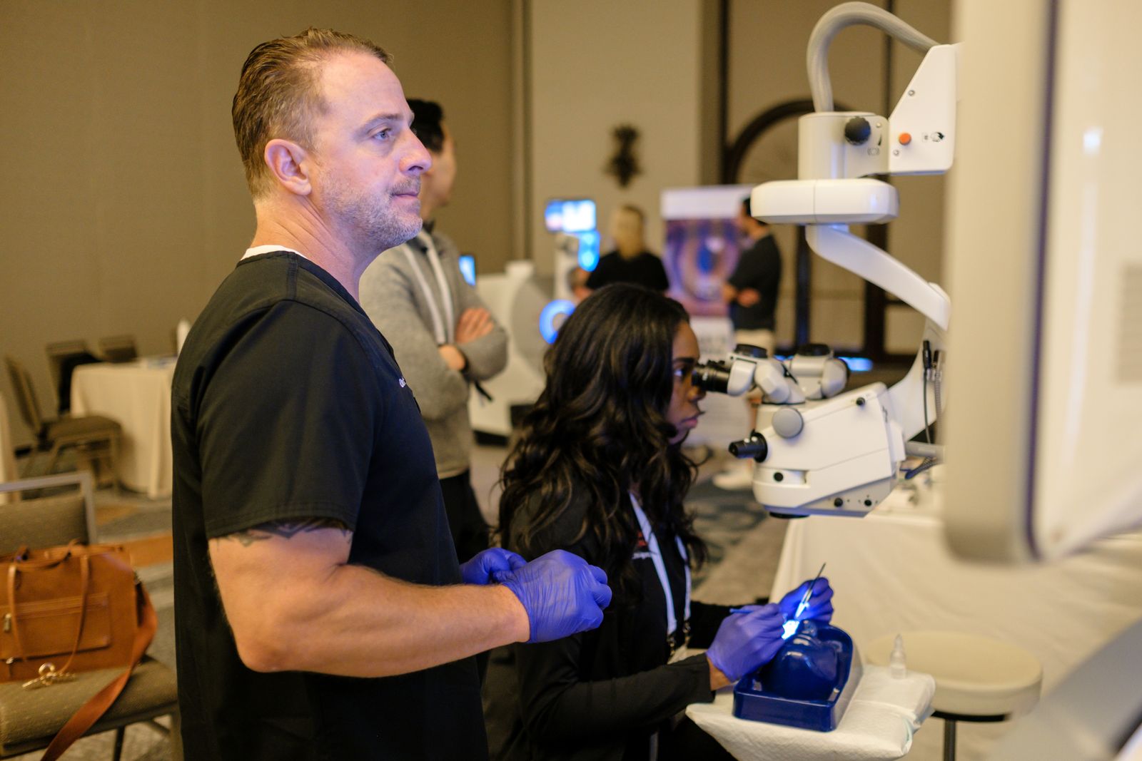 A resident and an instructor working together at a microscope station