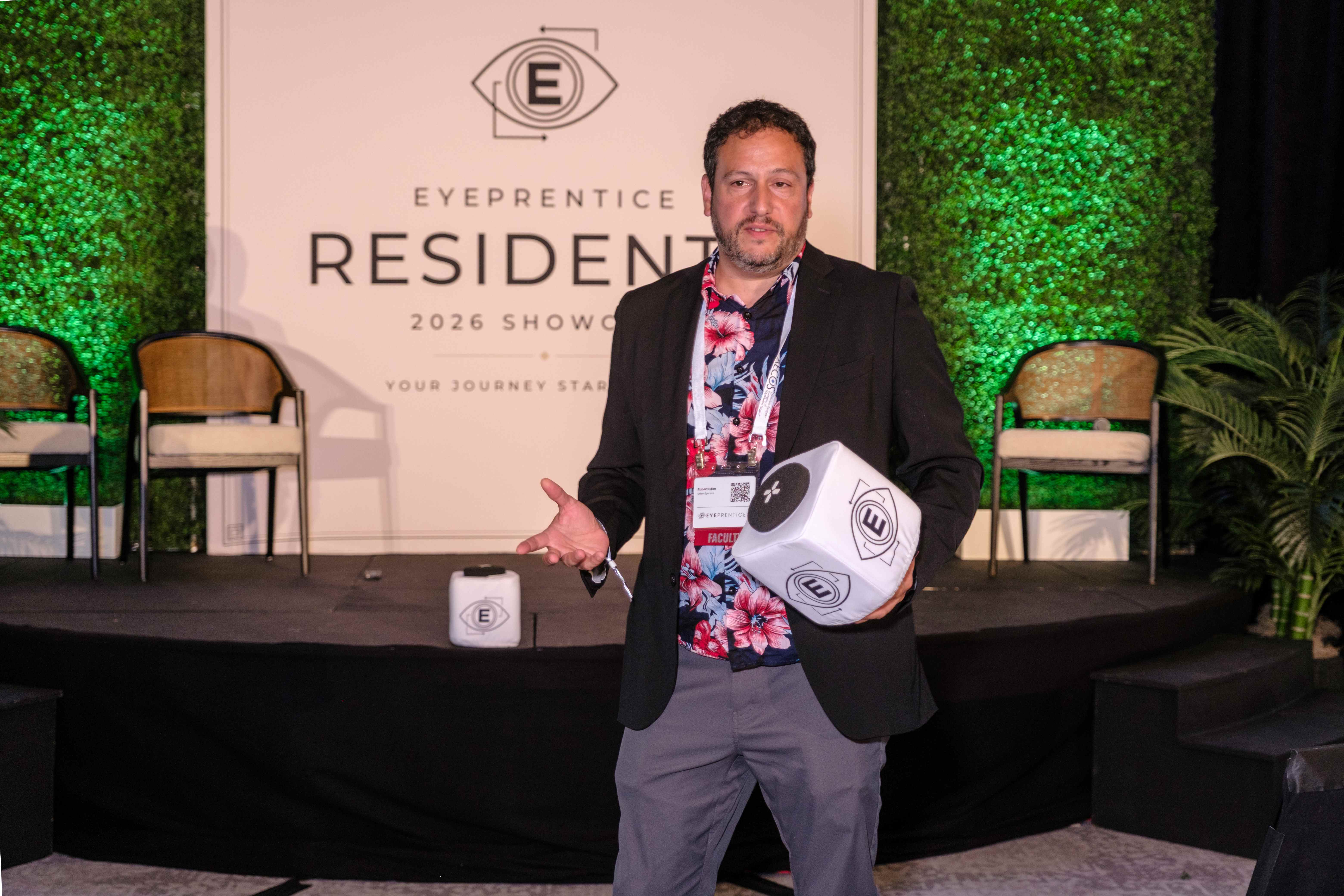 A faculty member holding an Eyeprentice logo cube on stage